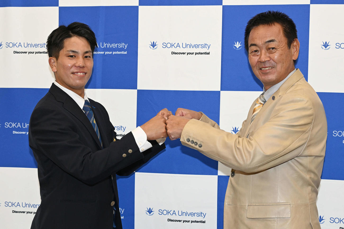 指名あいさつを受けた巨人ドラフト4位の創価大・門脇（左）は水野スカウト部長とグータッチを交わす（撮影・滝沢徹郎）