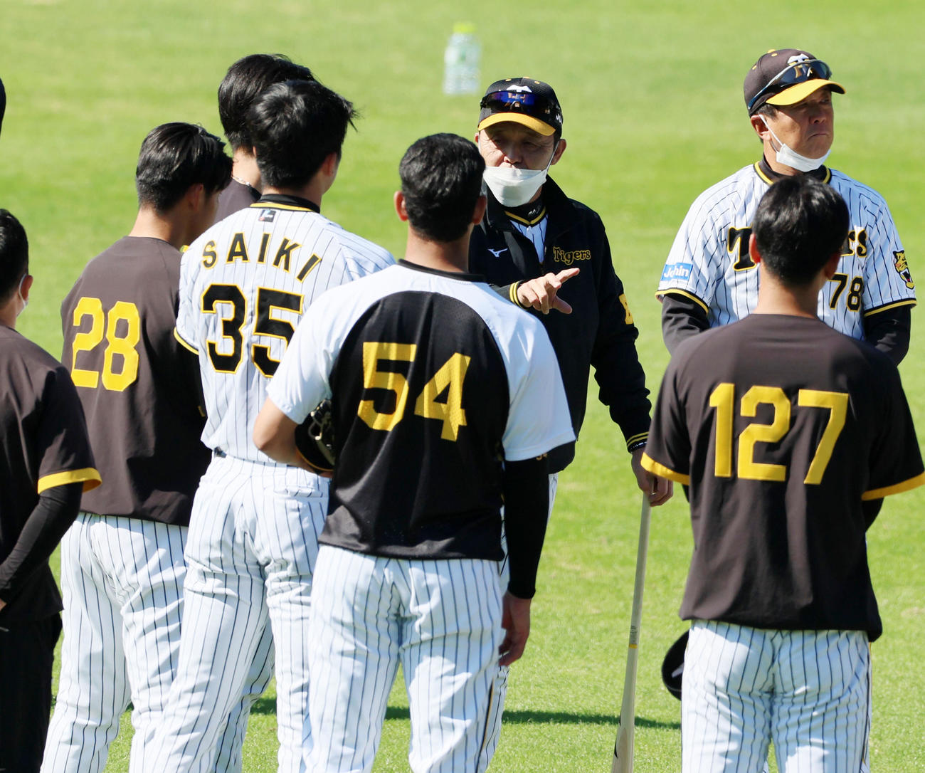 投手陣を集め話をする岡田彰布監督。後方は守備練習する野手陣（撮影・加藤哉）