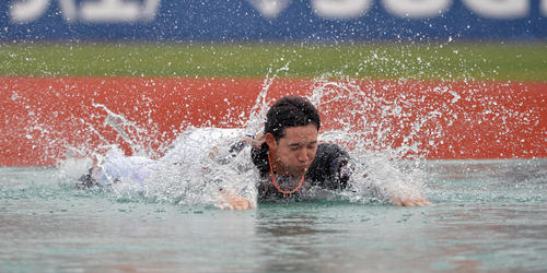 試合が雨天中止となり、水しぶきを上げ一塁にヘッドスライディングする日本ハム杉谷（14年6月7日撮影）