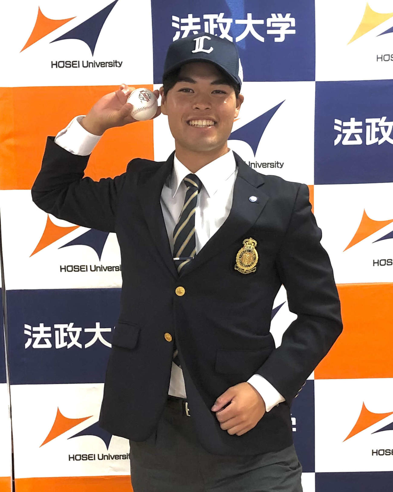 報道陣のリクエストに応じ、笑顔で送球のポーズをする法大・是沢（撮影・上田悠太）