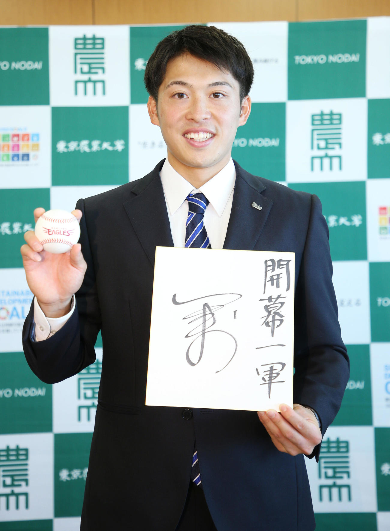 指名あいさつを受けた楽天ドラフト4位の東農大オホーツク・伊藤投手は開幕一軍と書いた色紙とボールを持ち笑顔を見せる（撮影・宮地輝）