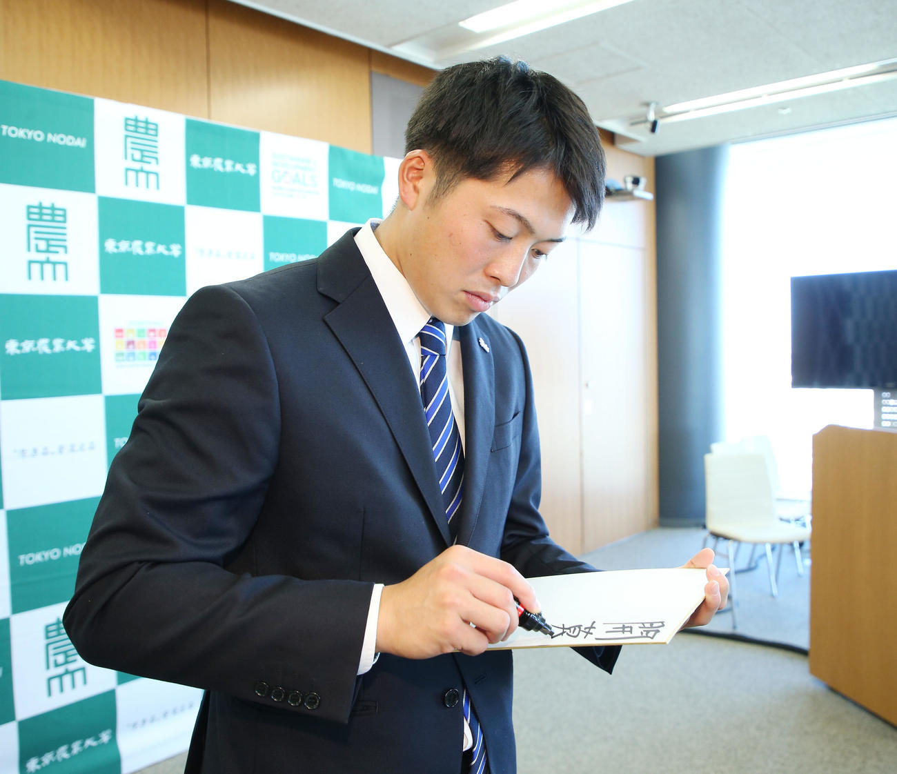 指名あいさつを受けた楽天ドラフト4位の東農大オホーツク・伊藤投手は色紙に目標を書く（撮影・宮地輝）