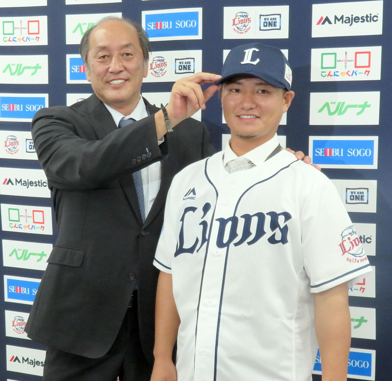 西武復帰会見後に渡辺久信ゼネラルマネジャー（左）から帽子をかぶせてもらう佐藤龍世（撮影・鎌田直秀）