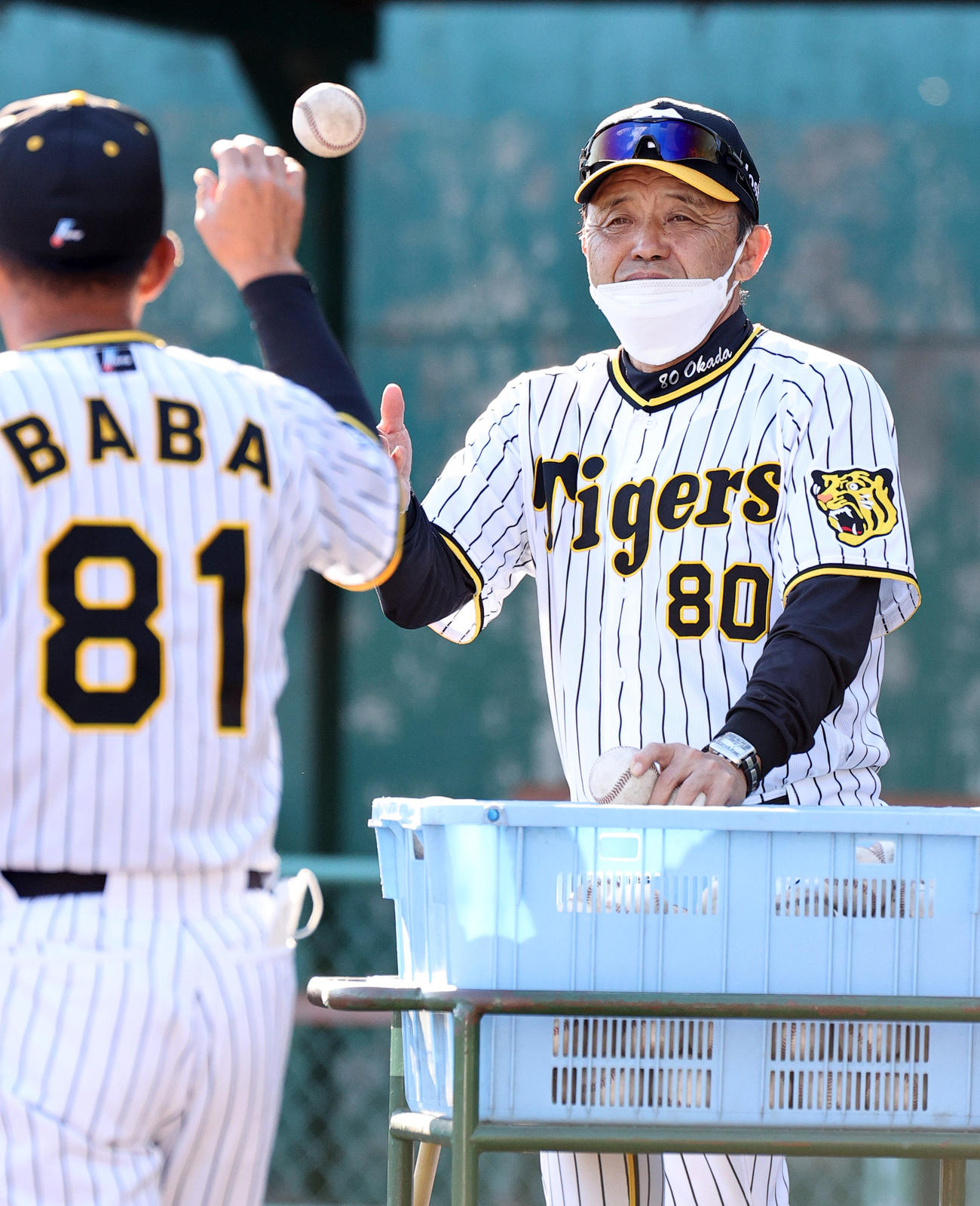 ノッカーの馬場コーチ（手前）にボールをトスする岡田監督（撮影・上山淳一）