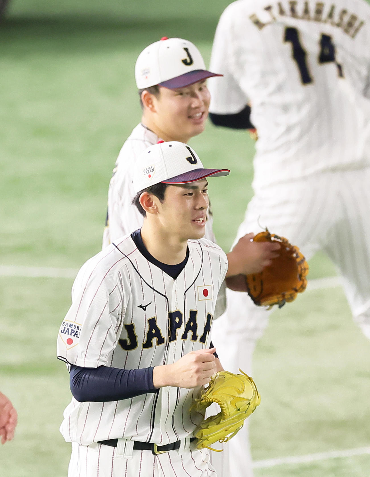 練習中、投内連係を行う侍ジャパンの佐々木朗（手前）を笑顔で見つめる村上（撮影・足立雅史）