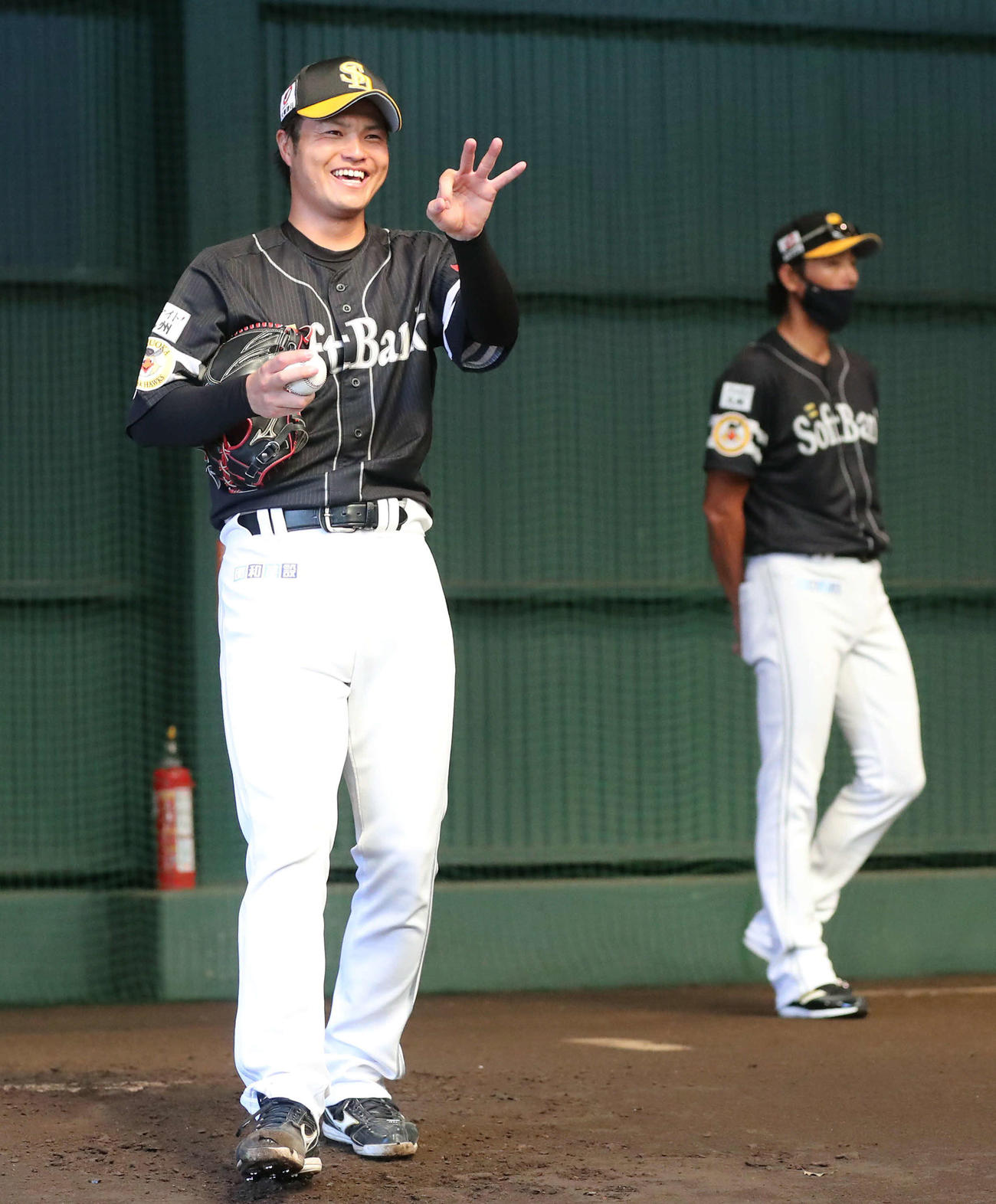 ブルペンで笑顔を見せる甲斐野。右奥は斉藤コーチ（撮影・梅根麻紀）