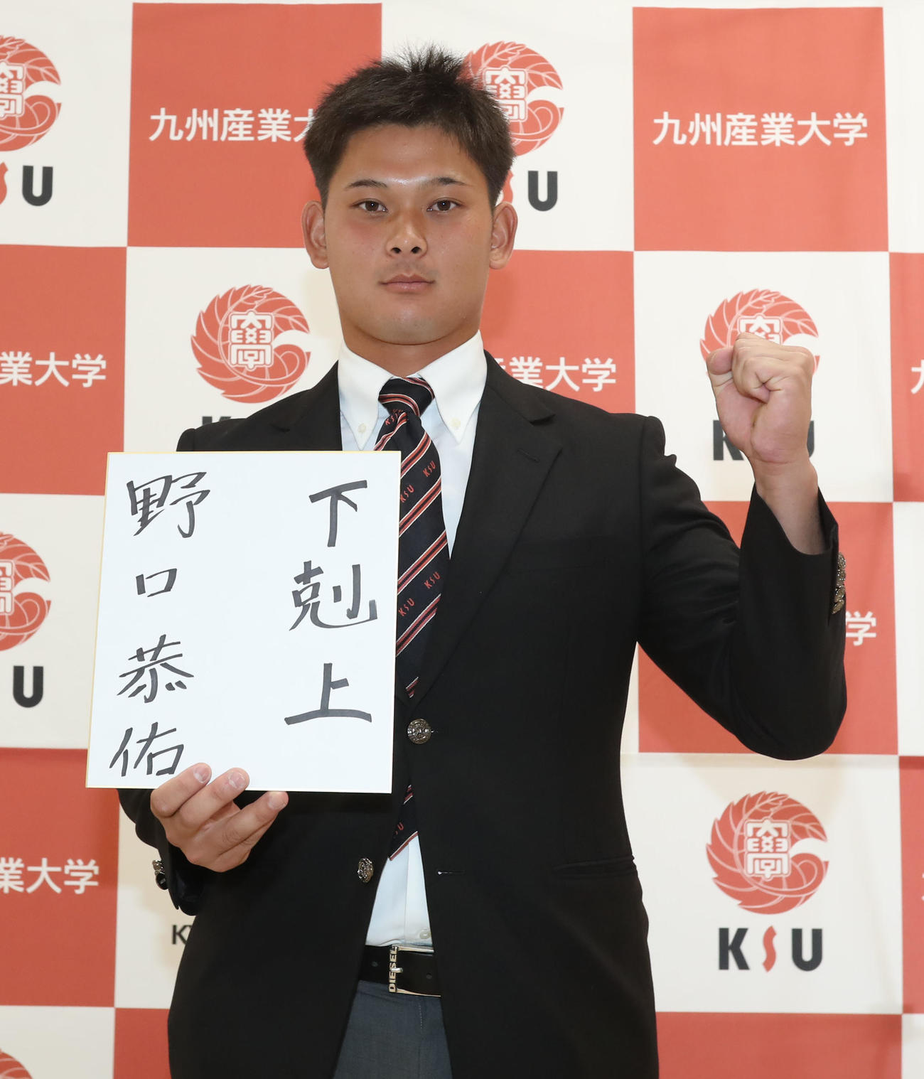 今後の目標を色紙に記し、ガッツポーズをする育成ドラフト1位の九産大・野口（撮影・屋方直哉）