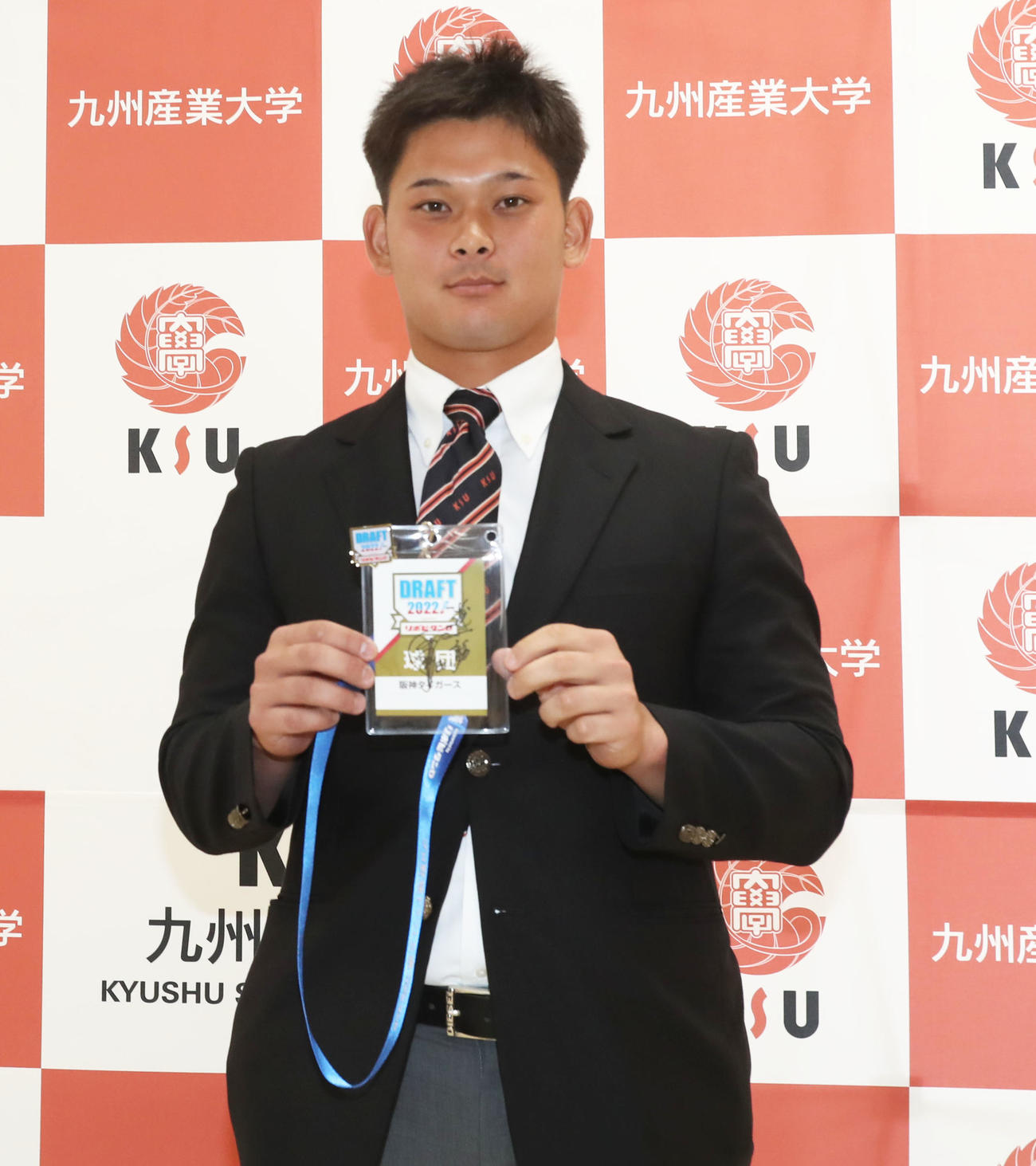 ドラフト会議のパスを手に写真に納まる育成ドラフト1位の九産大・野口（撮影・屋方直哉）