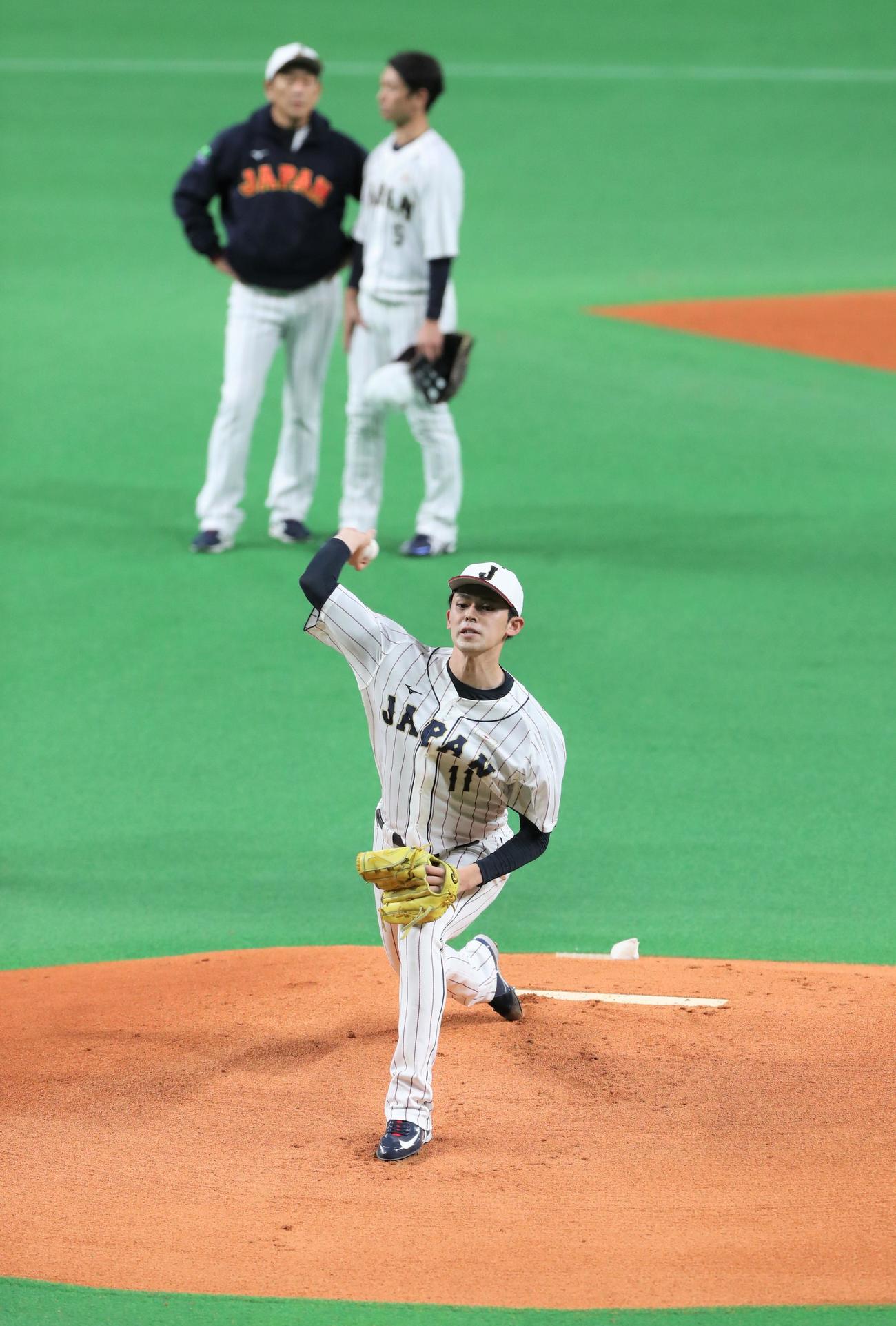 侍ジャパンシリーズ2022　日本対オーストラリア　公式練習　マウンドで投球する佐々木朗。後方左は栗山監督（撮影・黒川智章）