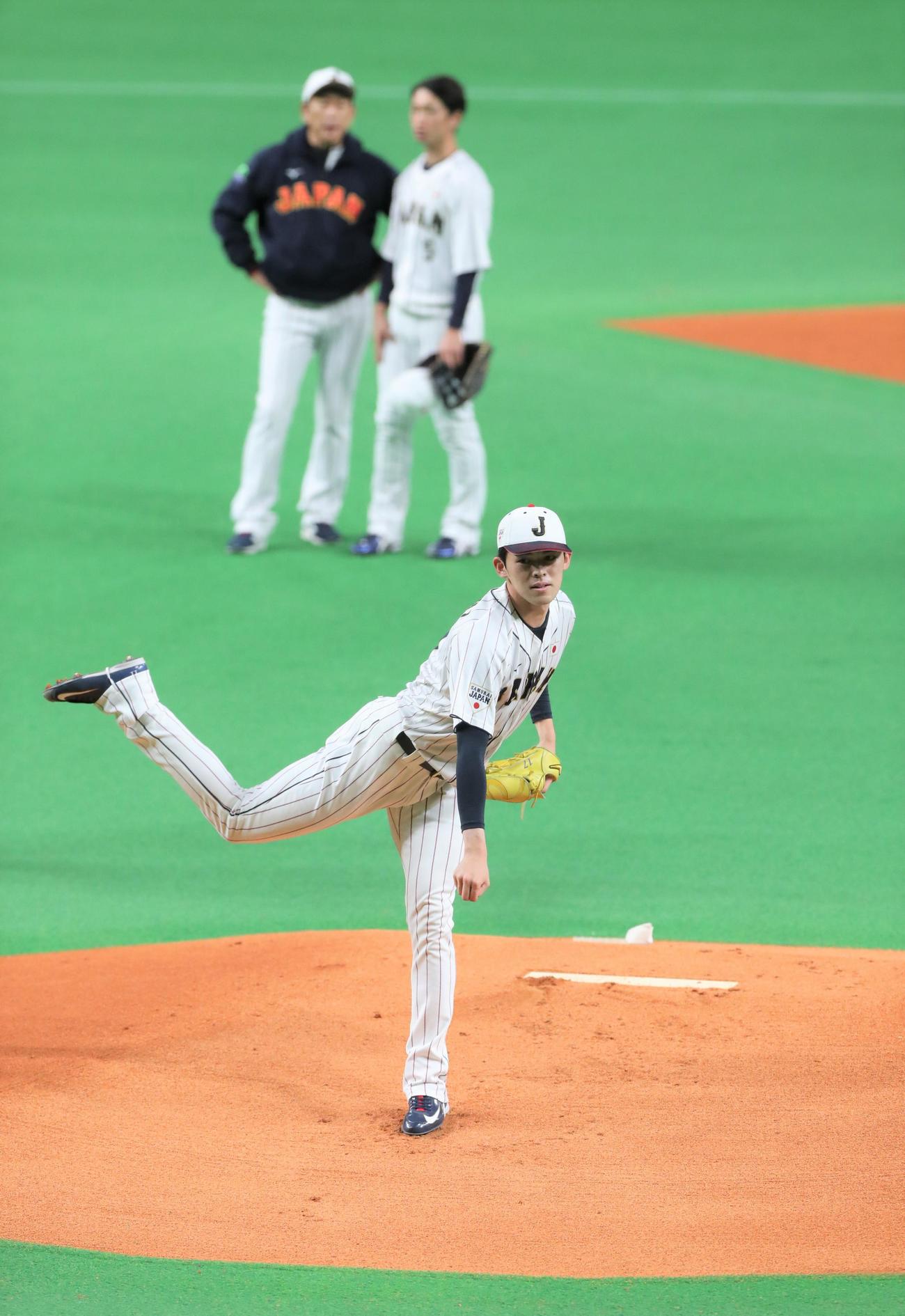 侍ジャパンシリーズ2022　日本対オーストラリア　公式練習　マウンドで投球する佐々木朗。後方左は栗山監督（撮影・黒川智章）