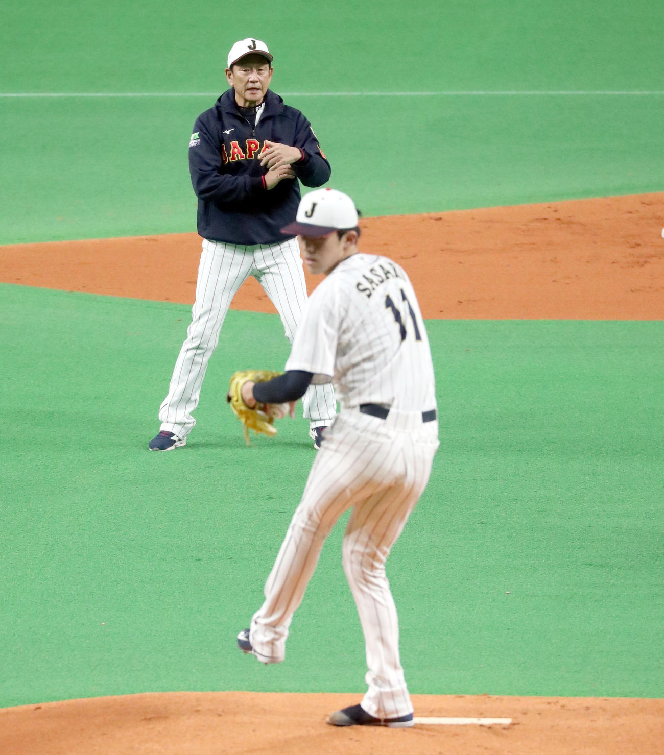 侍ジャパン栗山監督（左後方）は佐々木朗の投球を見つめる（撮影・佐藤翔太）