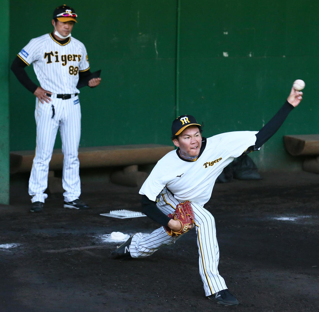 1段モーションで投球する及川。左は安藤投手コーチ（撮影・上山淳一）