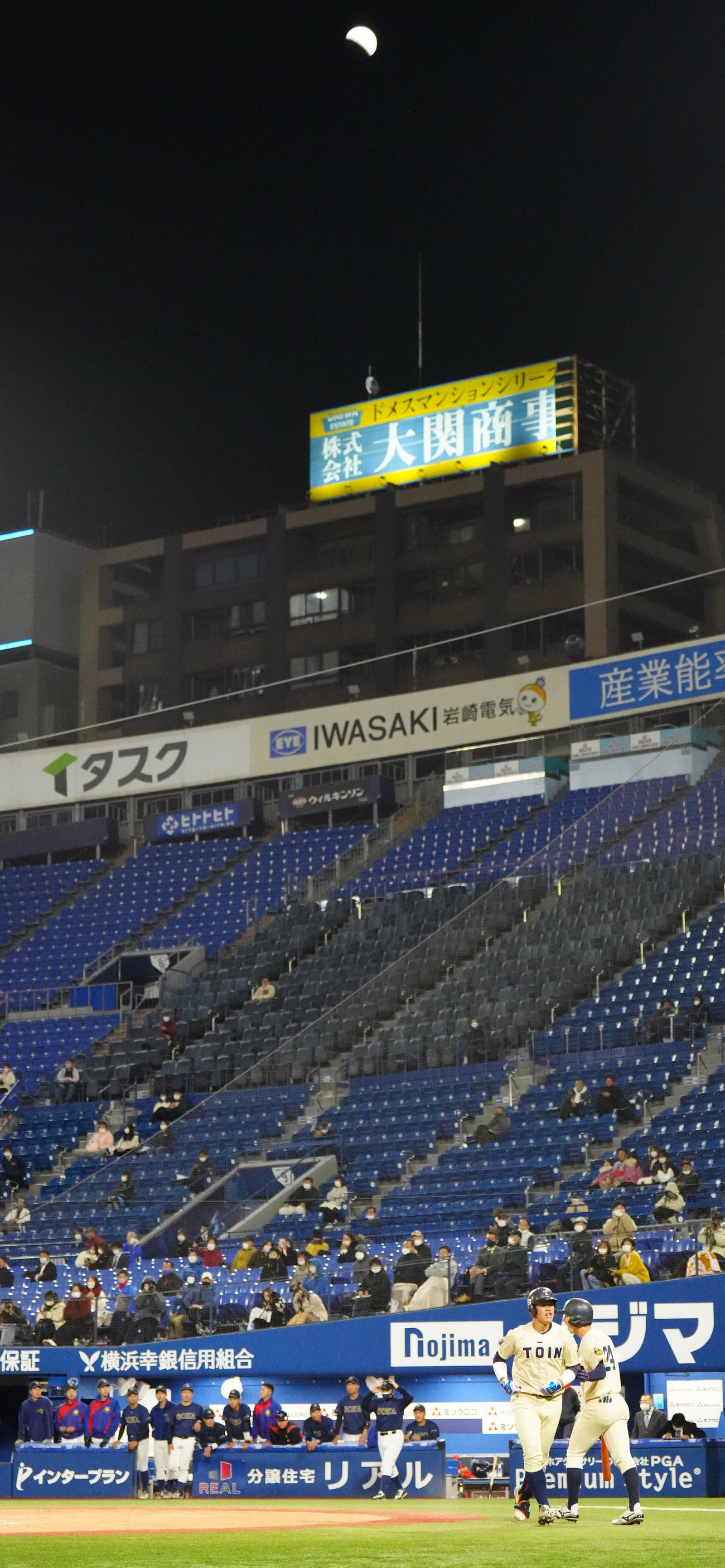 桐蔭横浜大対創価大　9回裏桐蔭横浜大1死、上空の月が部分食になる中、ソロ本塁打を放った吉田賢（手前左）（撮影・江口和貴）