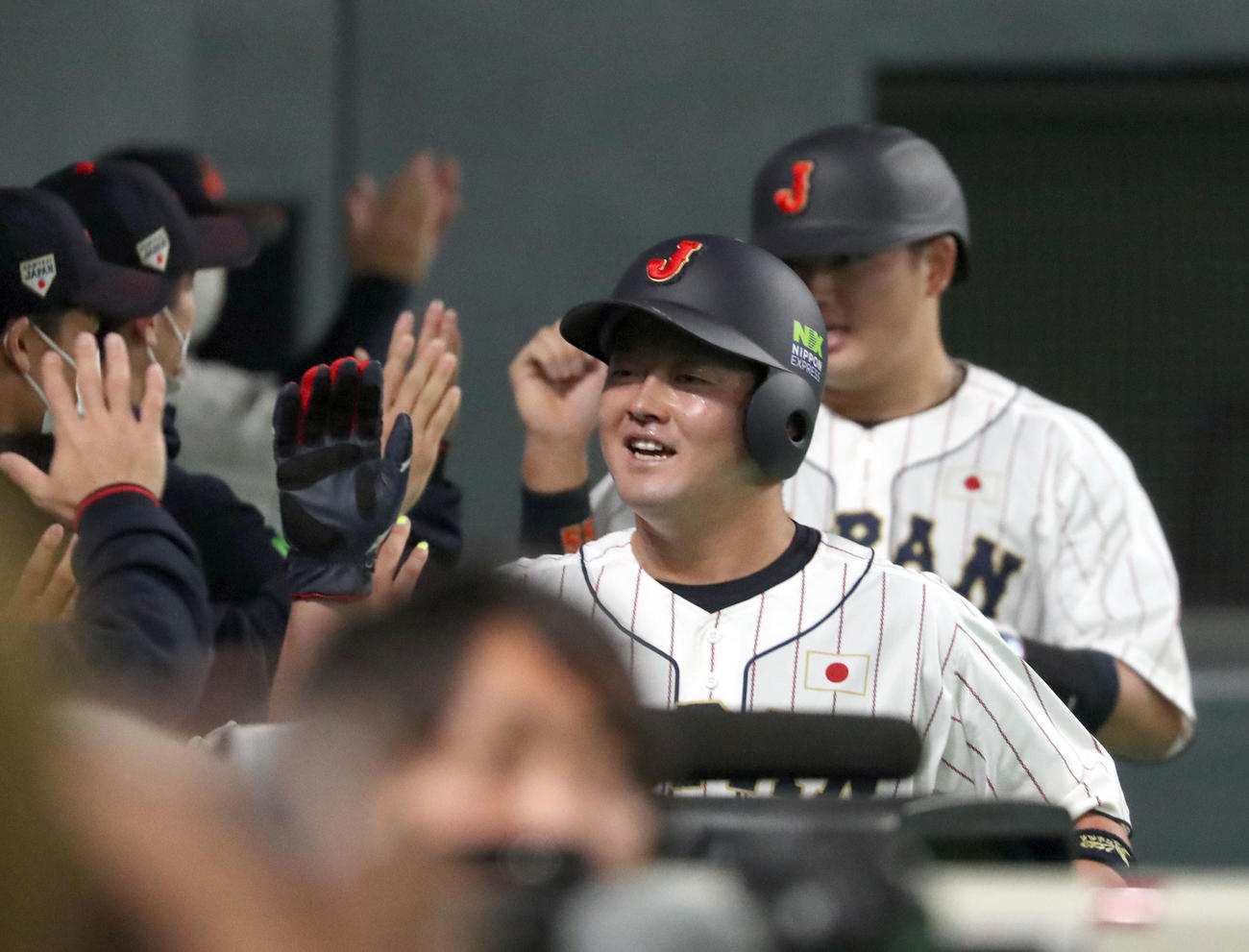 日本対オーストラリア　2回裏日本1死二、三塁、岡本和の中前2点適時打で生還しナインに出迎えられる牧（中央）と村上（撮影・佐藤翔太）