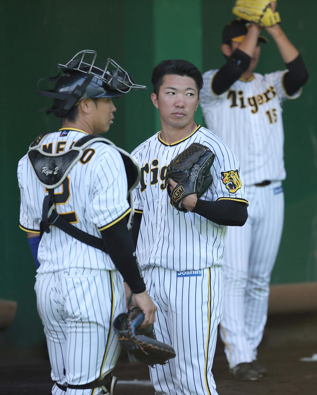 ブルペンで投げ終わった石井（中央）にアドバイスする梅野。右は西純（撮影・上山淳一）