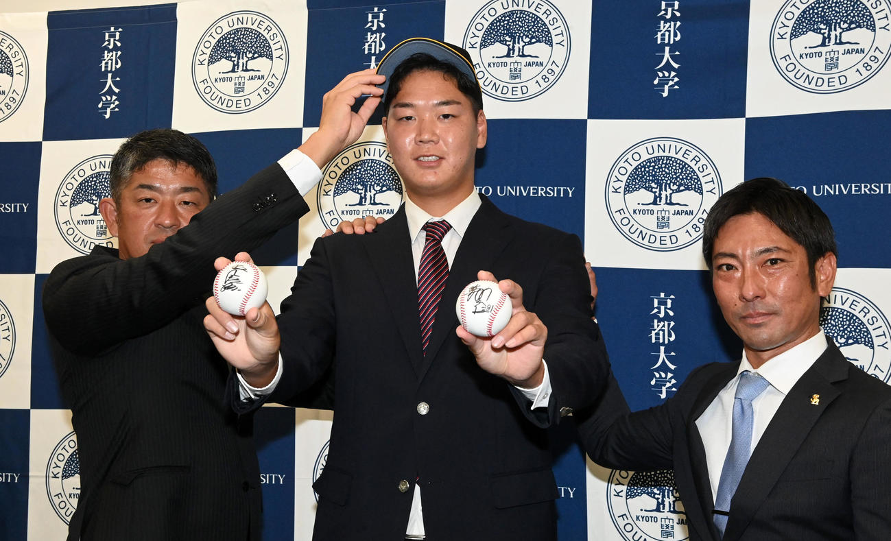 ソフトバンクから指名あいさつを受けた京大・水口（中央）はプレゼントされた王球団会長（右手）、藤本監督のサインボールを手に福山（左）、稲嶺両スカウトと笑顔を見せる（撮影・前岡正明）