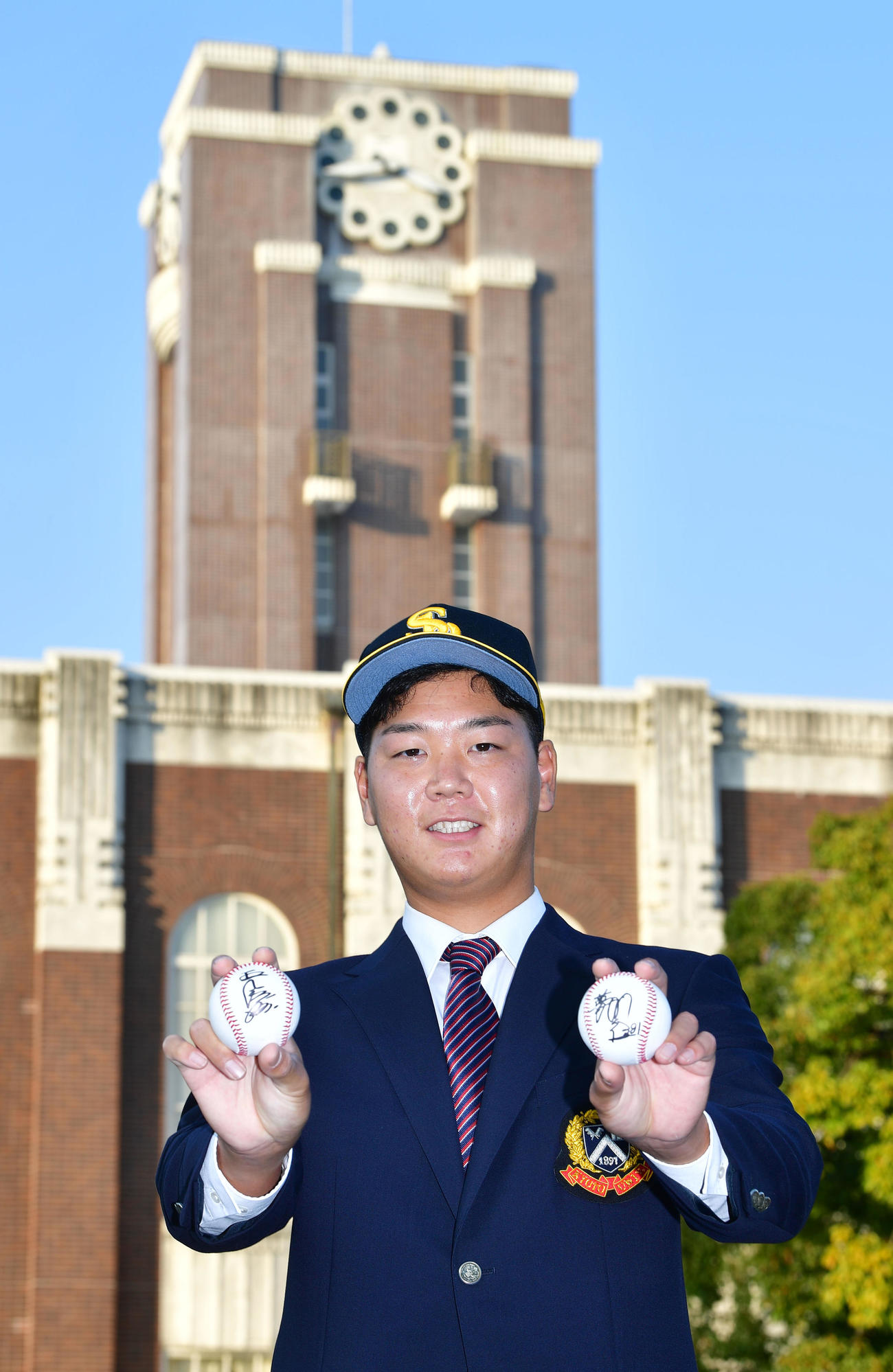 ソフトバンクから指名あいさつを受けた京大水口はプレゼントされた王球団会長（右手）、藤本監督のサインボールを手に笑顔を見せる（撮影・前岡正明）