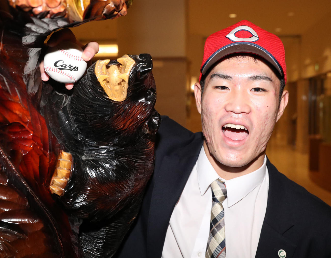 広島ドラフト1位指名の苫小牧中央・斉藤は仮契約を終え、木彫りの熊と記念撮影をする（撮影・佐藤翔太）
