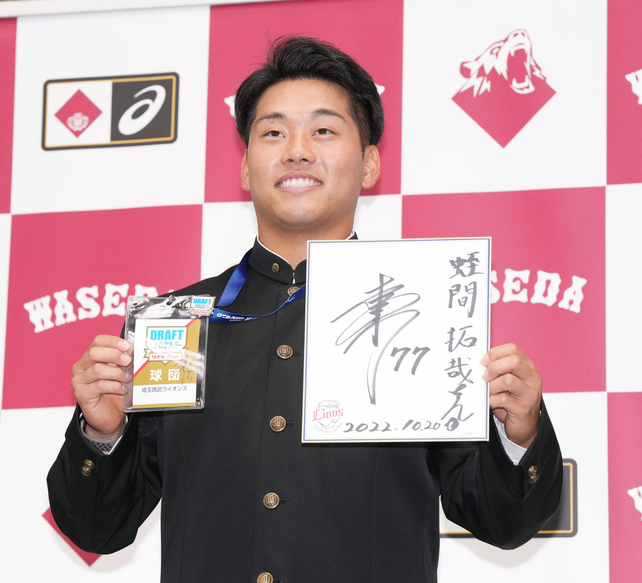 西武から指名あいさつを受け、ドラフト会議で松井監督が使用したパスとサイン色紙を笑顔で手にする早大・蛭間（撮影・菅敏）