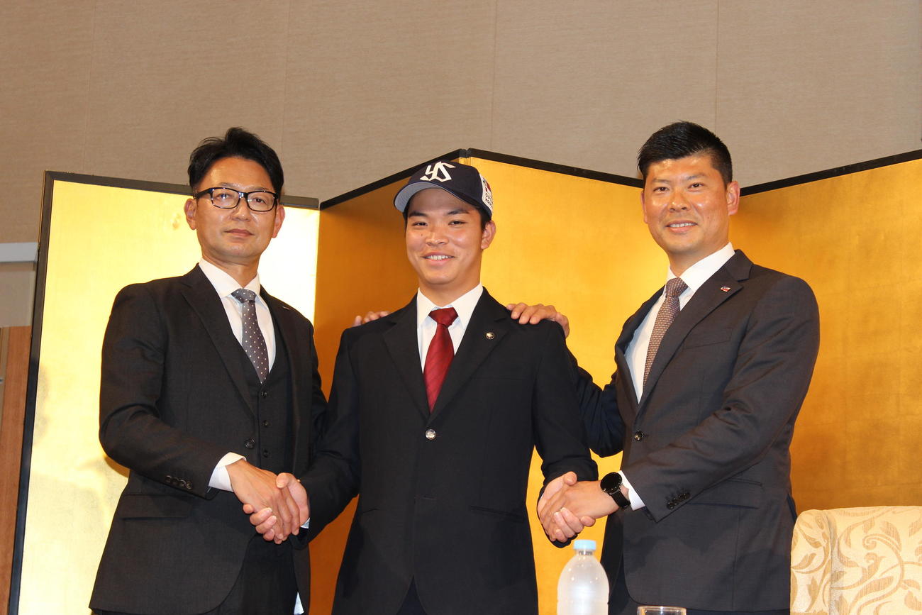ヤクルト2位西村瑠伊斗（中央）と仮契約を結び握手をする橿渕スカウトグループデスク（左）と阿部健太スカウト（右）＝2022年11月13日（撮影・柏原誠）