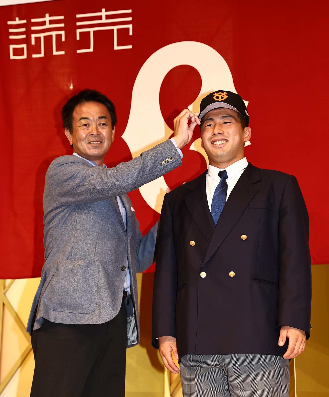仮契約を終え水野スカウト部長（左）から帽子を被せてもらう巨人ドラフト1位の高松商・浅野（撮影・上田博志）