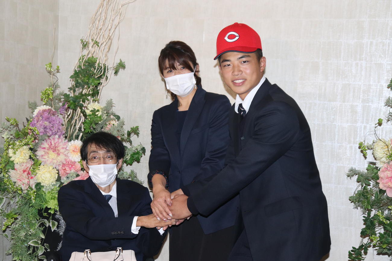 父・清司さん（左）、母・智美さん（中央）と記念撮影する広島と仮契約した2位指名の利根商・内田（撮影・星夏穂）