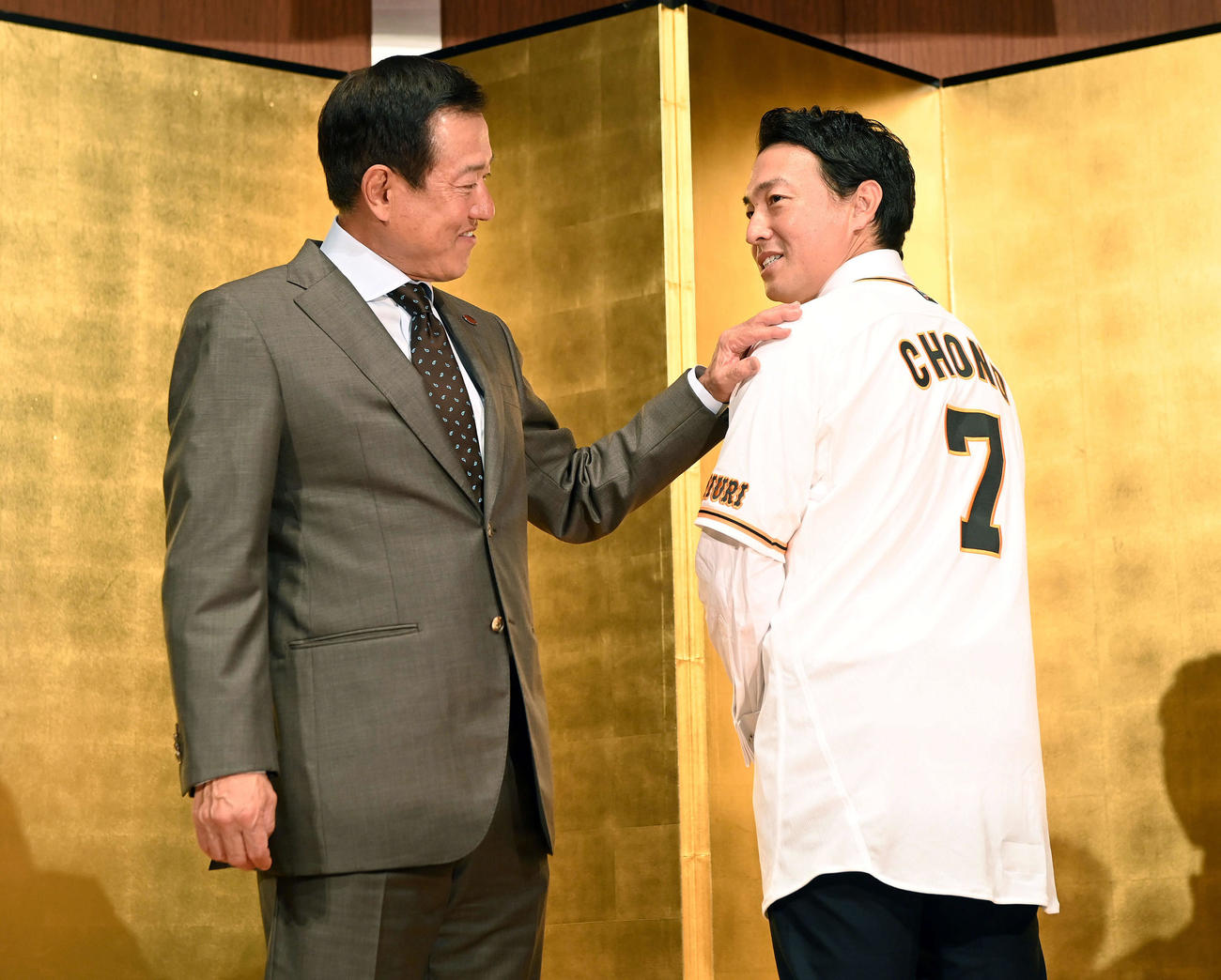 背番号「7」に袖を通し笑顔を見せる巨人長野。左は原監督（撮影・たえ見朱実）