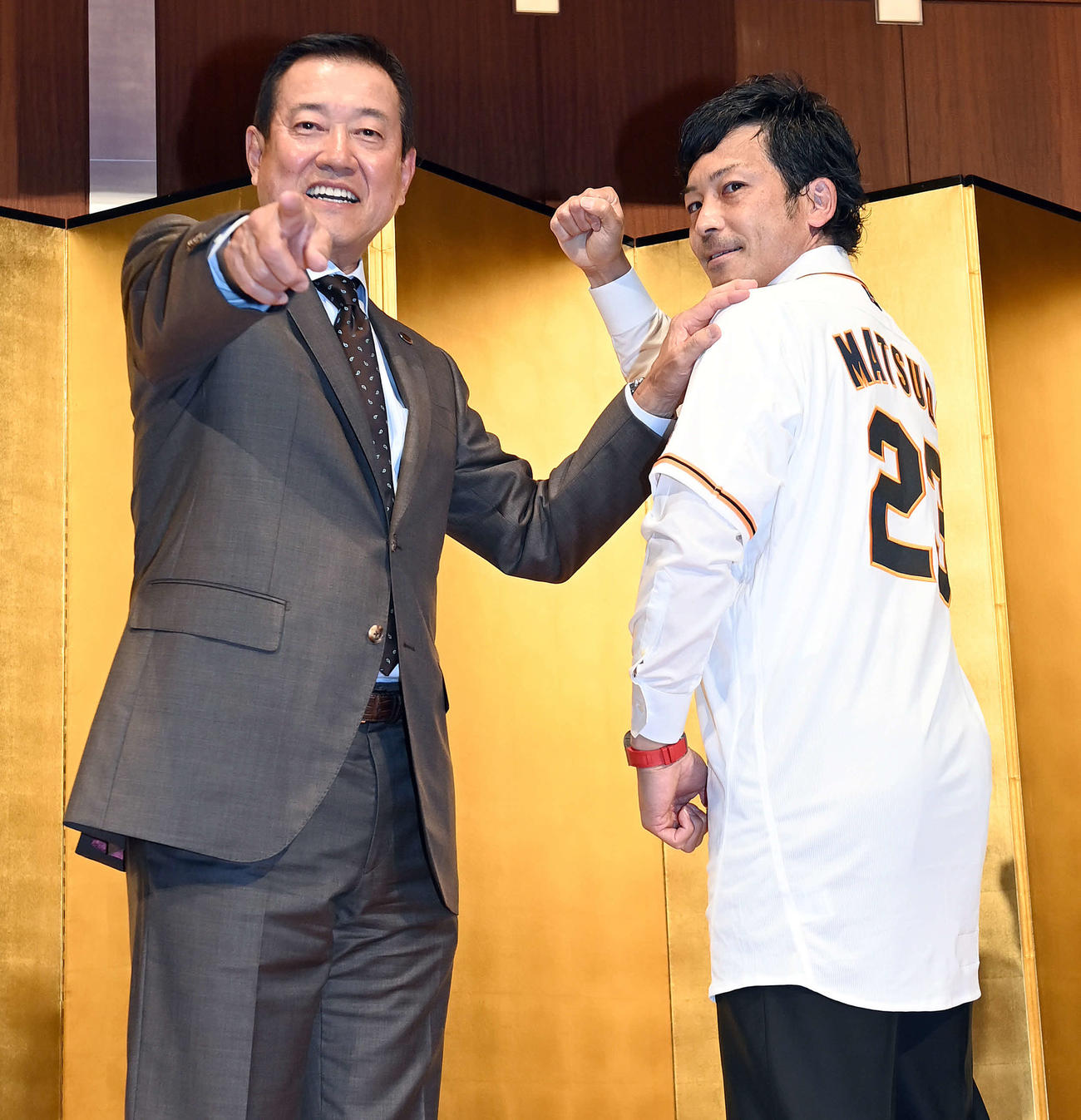 背番号「23」のユニホームに袖を通しポーズを決める巨人松田。左は原監督（撮影・たえ見朱実）