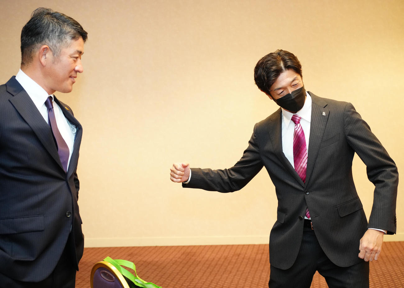 ソフトバンクと仮契約したドラフト6位の桐蔭横浜大・吉田に熱男ポーズを指南する松本アマスカウト（右）。左は福山アマスカウトチーフ（撮影・江口和貴）