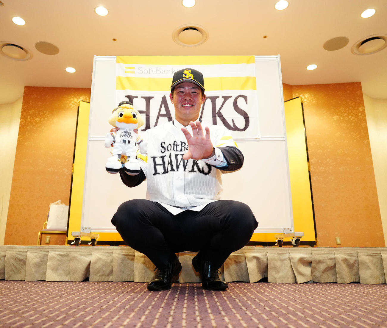 ソフトバンクと仮契約し、捕手のポーズを見せるドラフト6位の桐蔭横浜大・吉田（撮影・江口和貴）