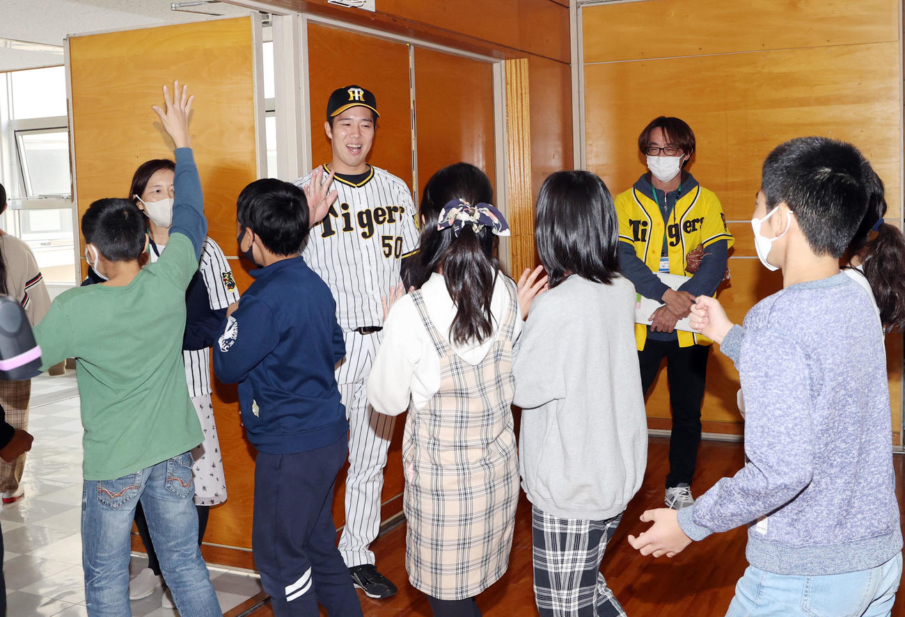 地元横浜市鶴見区にある上寺尾小学校を訪れ、別れ際に子どもたちとタッチを交わす阪神青柳（撮影・狩俣裕三）
