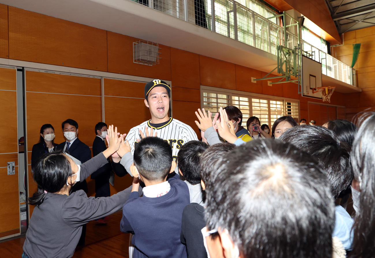 地元横浜市鶴見区にある上寺尾小学校を訪れ、別れ際に子どもたちからタッチ攻めに合う阪神青柳（撮影・狩俣裕三）