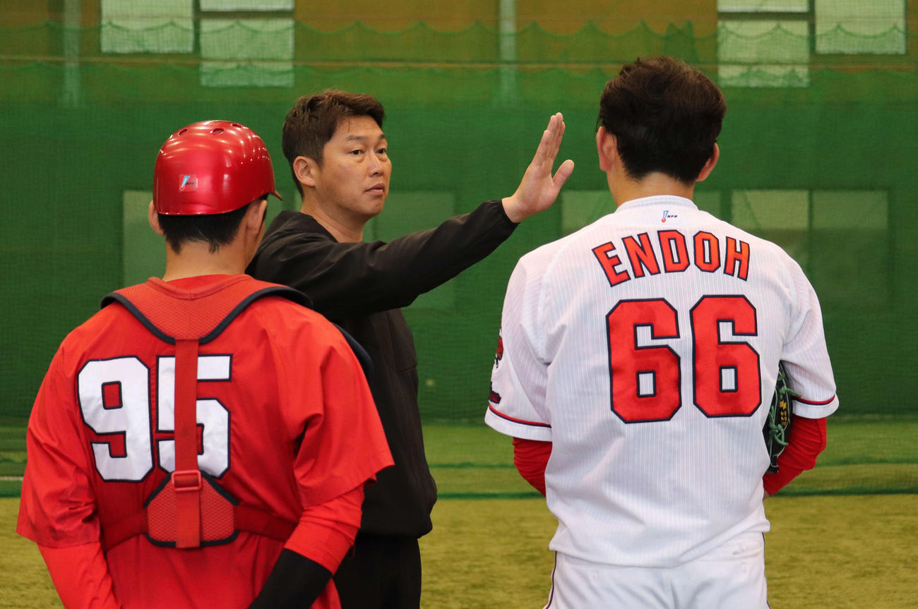 身ぶり手ぶりを交えながら広島遠藤淳志（右）を指導する新井監督（撮影・前原淳）