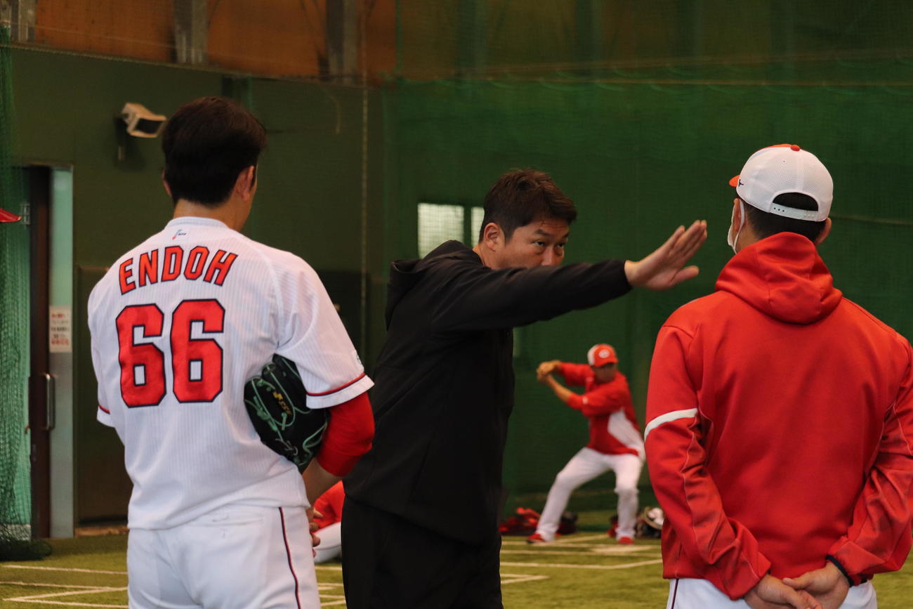 身ぶり手ぶりを交えながら広島遠藤淳志投手（写真左）を指導する新井貴浩監督（中央）（撮影・前原淳）