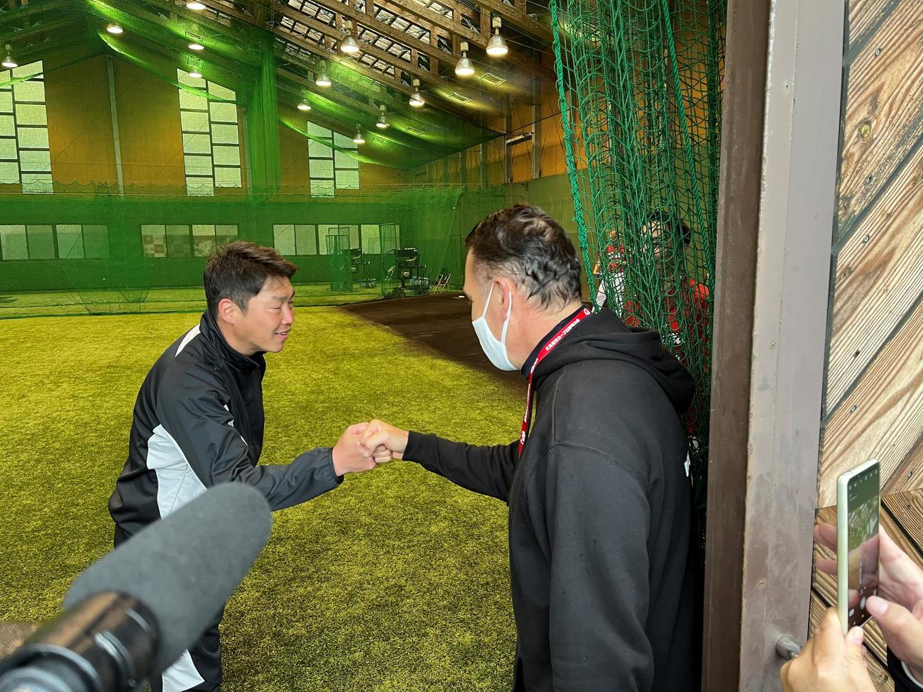広島ケムナ誠投手の父ブルースさん（右）とグータッチする広島新井監督