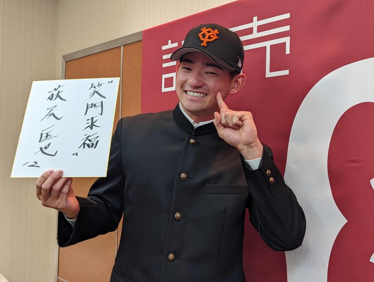 巨人と仮契約を結んだドラフト2位萩尾は、座右の銘「笑門来福」を手に笑顔を見せる（撮影・三須一紀）