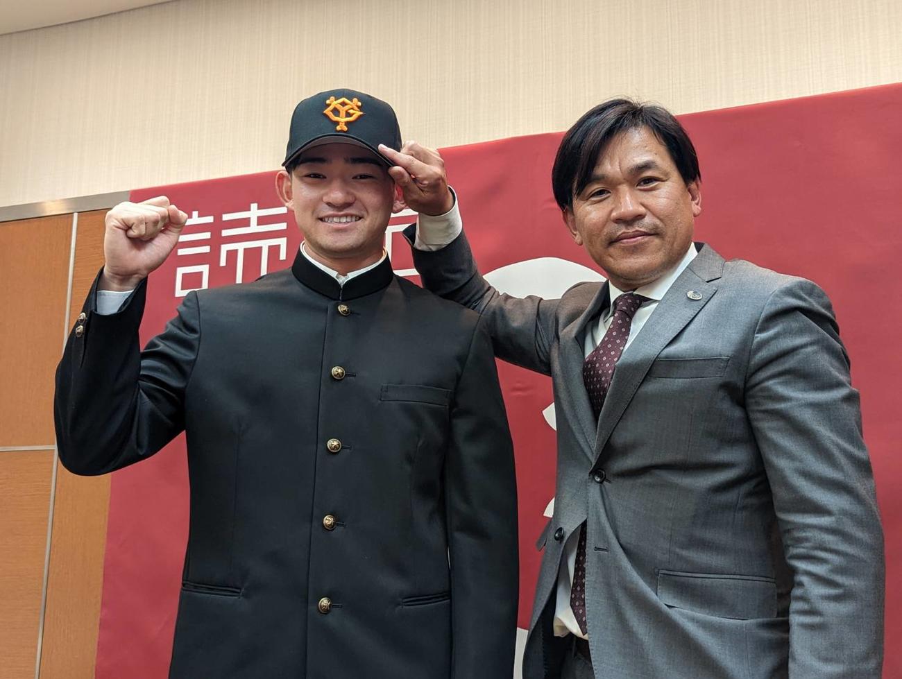 仮契約を結んだ巨人ドラフト2位萩尾匡也外野手（左）脇谷亮太スカウトから帽子をかぶせてもらう（撮影・三須一紀）