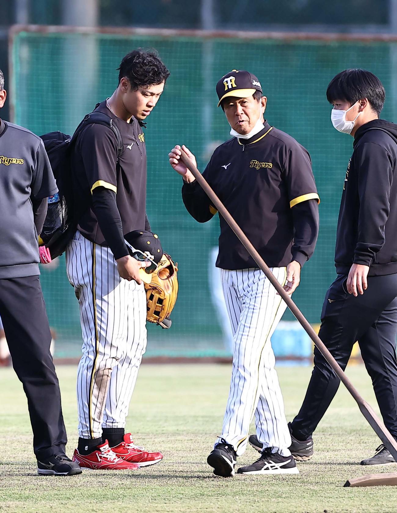 ノックを切り上げた佐藤輝（左）は平田ヘッドコーチに報告してからグラウンドを引き揚げる（撮影・上田博志）