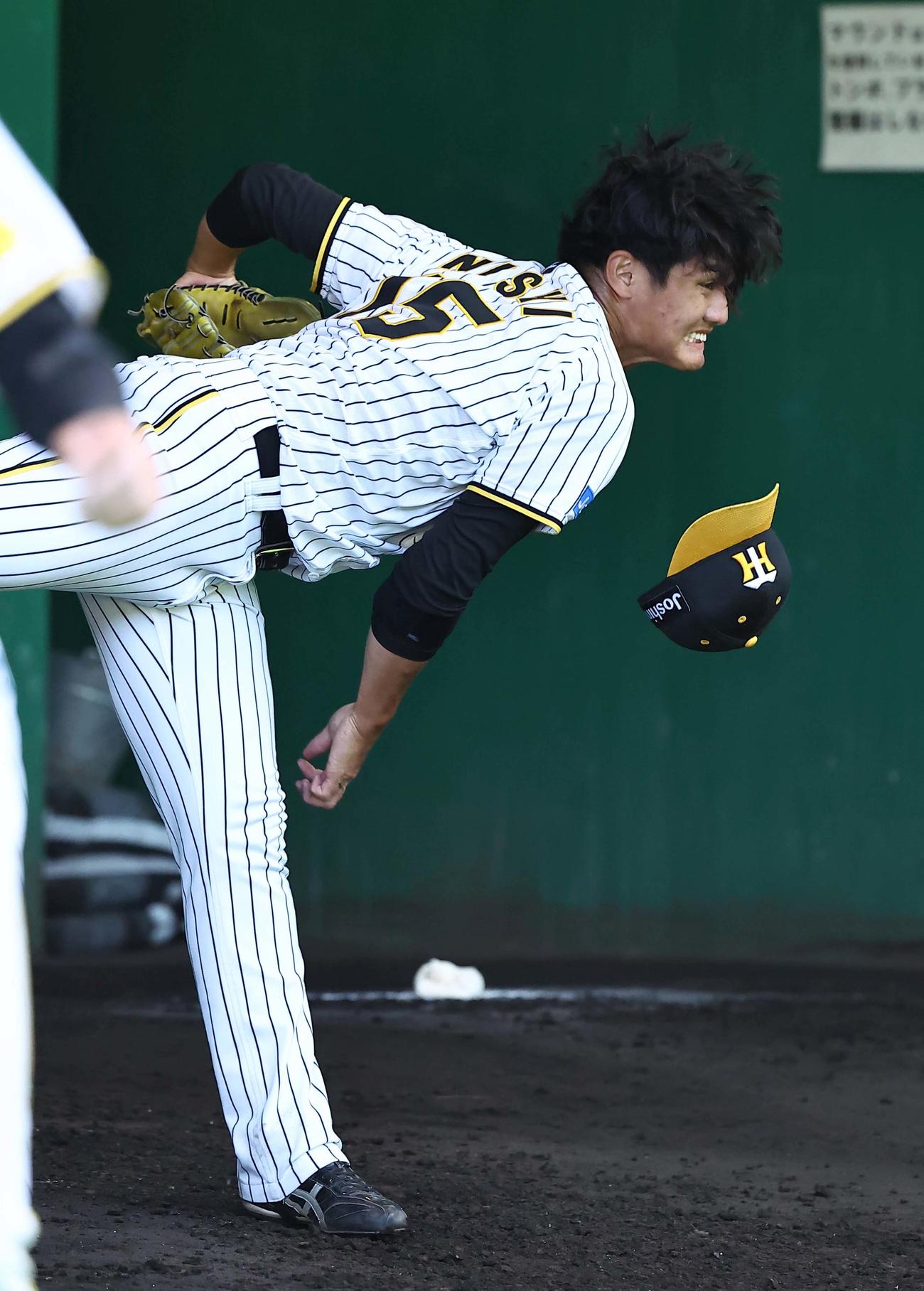 投球練習で帽子を飛ばす西純（撮影・上田博志）