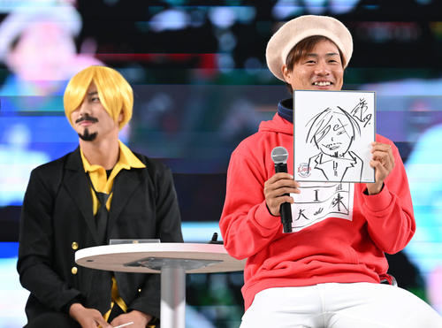 「ワンピース」のサンジのコスプレでモデルを務めた西武長谷川（奥）の似顔絵を披露する大曲（撮影・滝沢徹郎）
