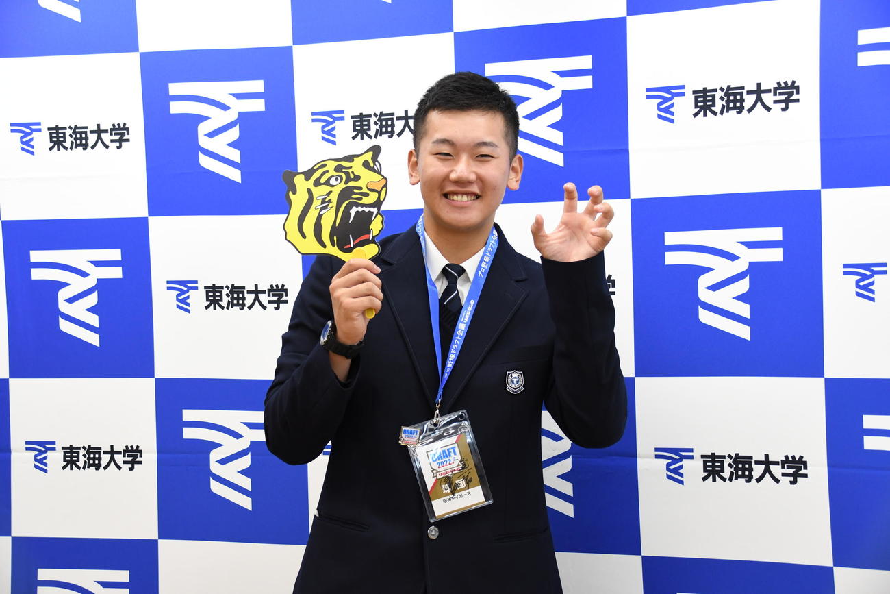 阪神のうちわを手にガオーポーズで笑顔を見せる東海大札幌高・門別（2022年10月25日撮影）