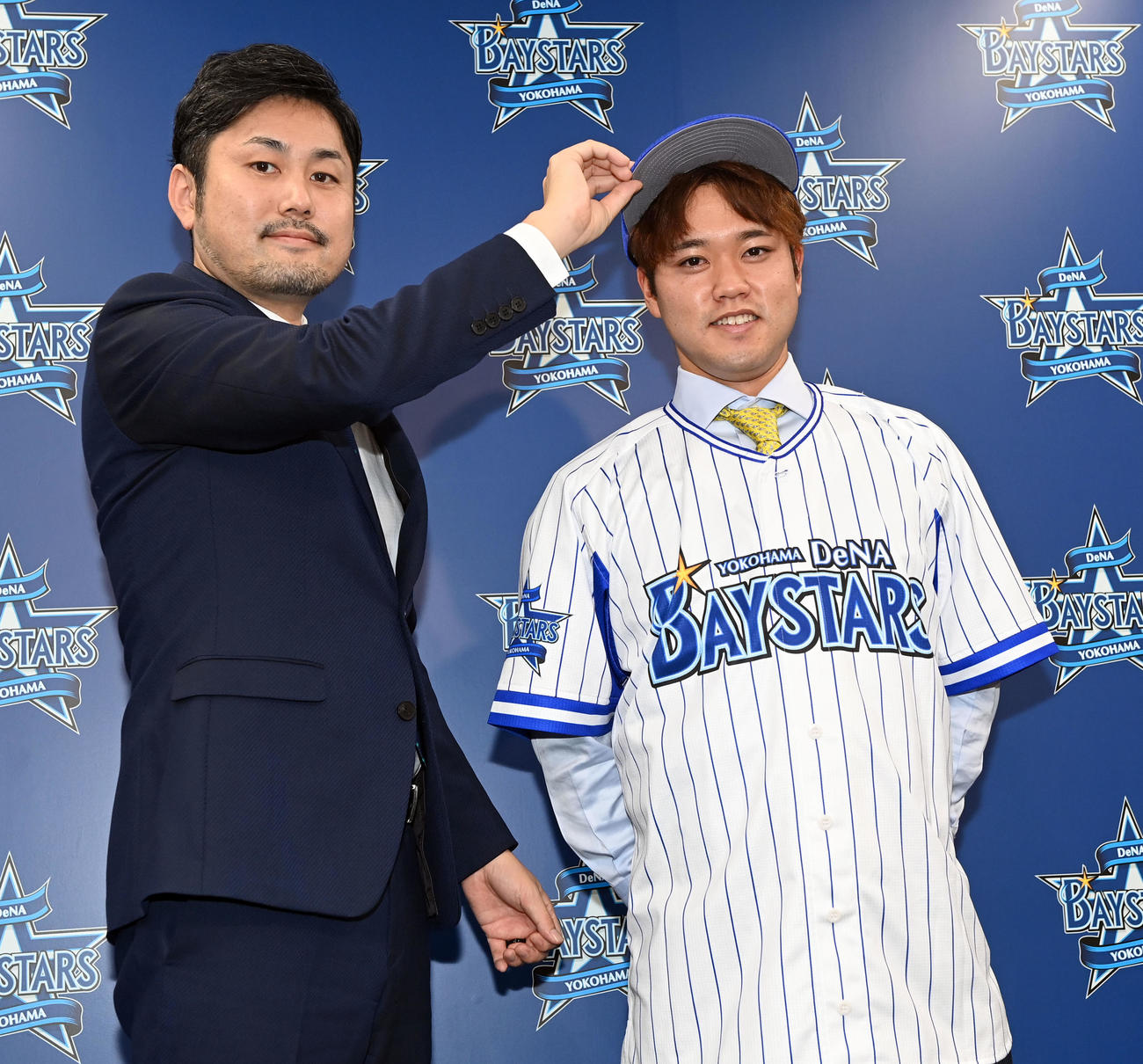 DeNAの入団会見で笑顔を見せる西巻。左は萩原チーム統括本部長（撮影・たえ見朱実）