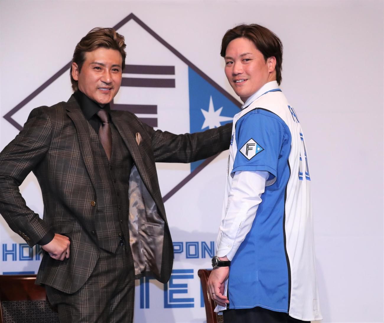 日本ハムのユニホームに袖を通し新庄剛志監督（左）とポーズをとる伏見（撮影・黒川智章）