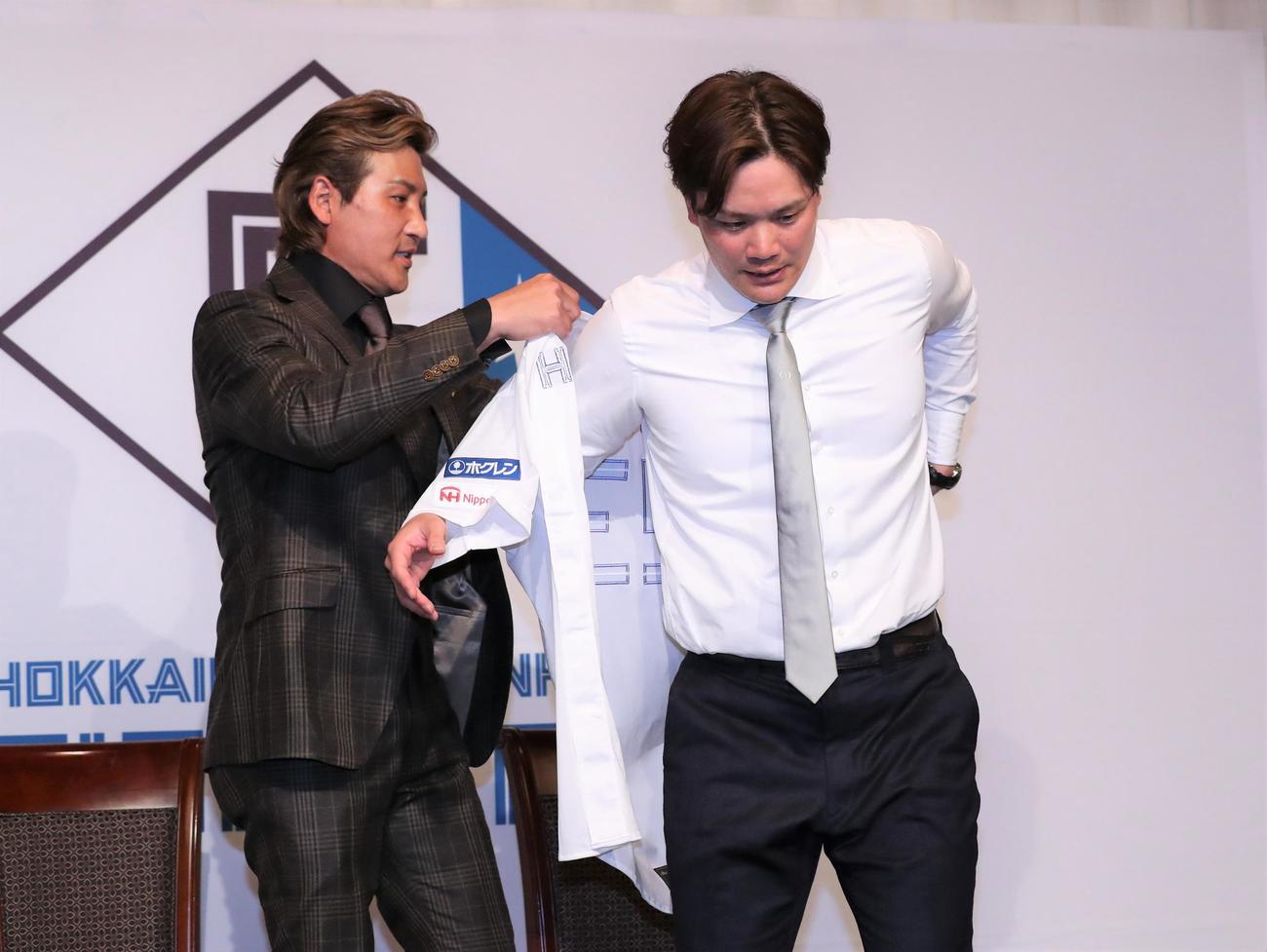 日本ハムの入団会見で新庄監督からユニホームを着せてもらう伏見（撮影・黒川智章）