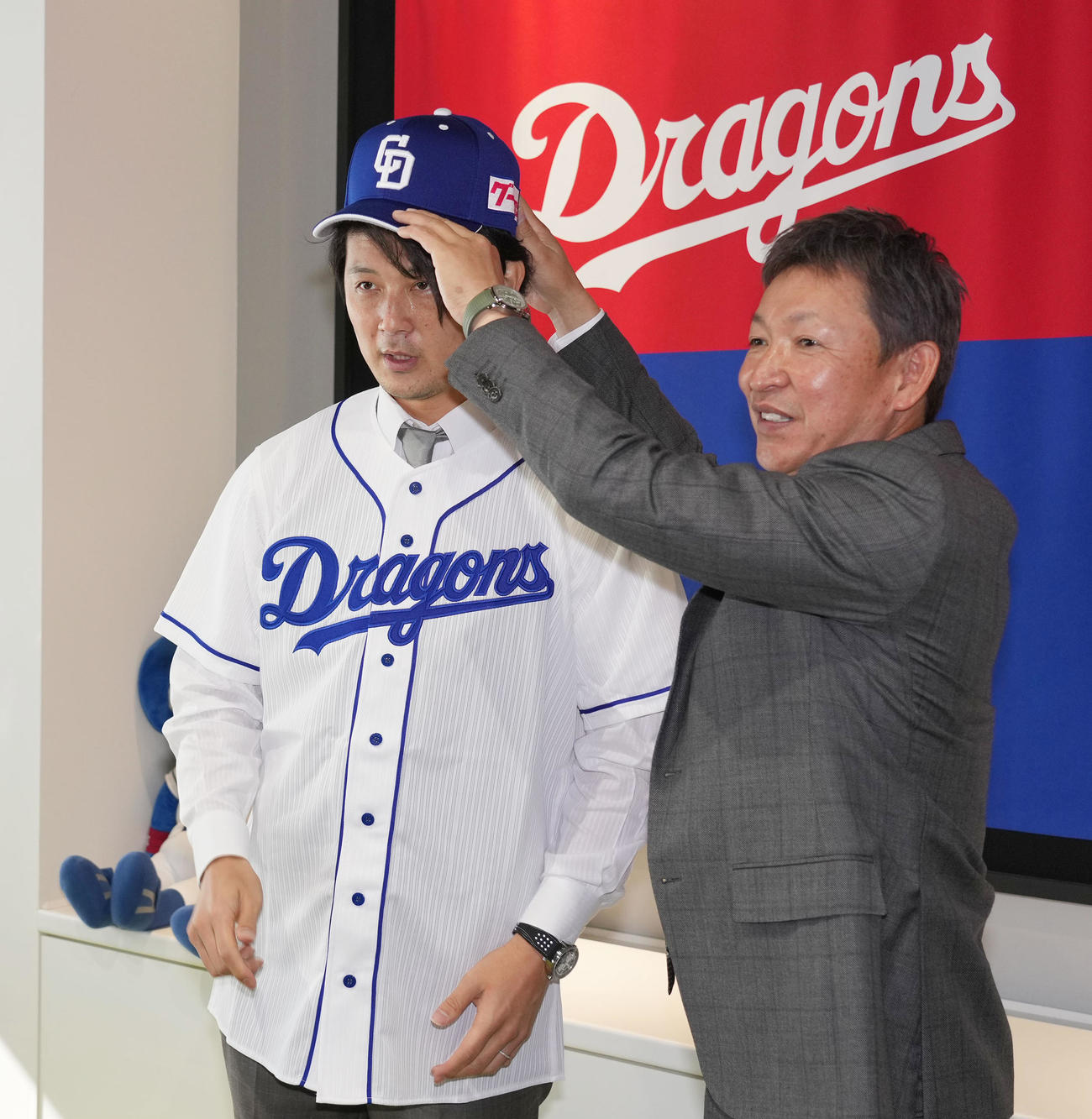会見後、ユニホームに袖を通し立浪監督から帽子をかぶせてもらう涌井（左）（撮影・森本幸一）