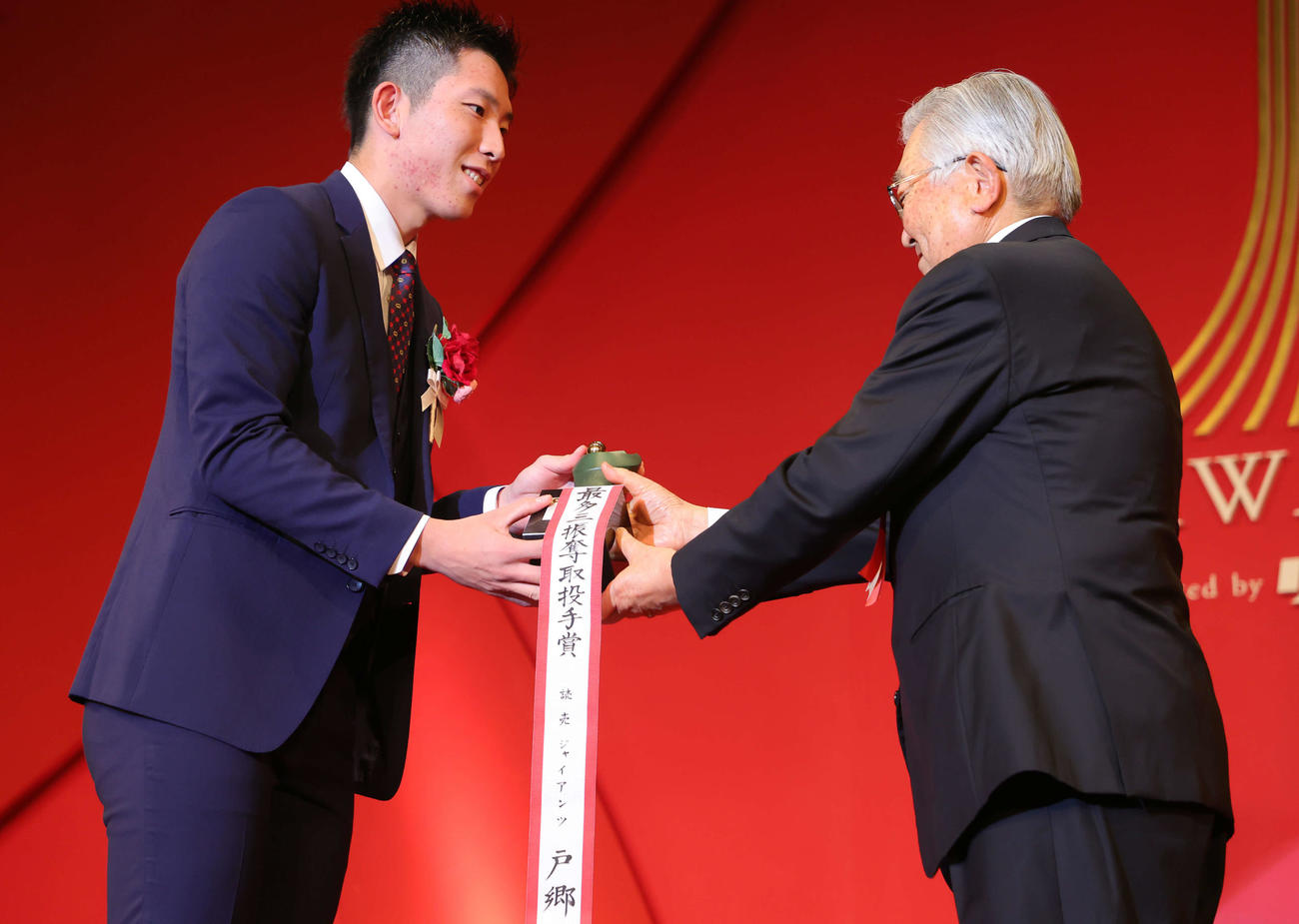 「NPB AWARDS 2022」でセ・リーグ最多三振奪取投手賞に輝いた巨人戸郷（左）は斉藤コミッショナーから笑顔でトロフィーを受け取る（代表撮影）