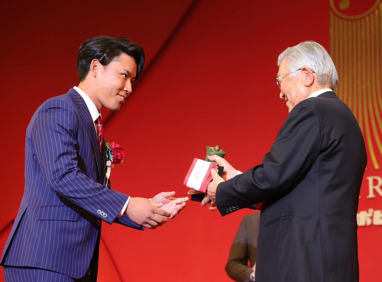 「NPB AWARDS 2022」でパ・リーグ最優秀中継ぎ投手賞に輝いた西武水上（左）はNPB斉藤コミッショナーから笑顔でトロフィーを受け取る（代表撮影）