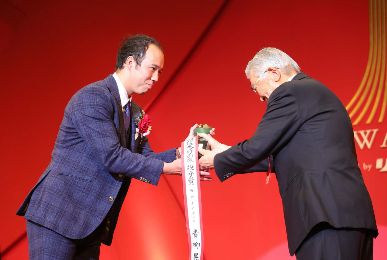 「NPB AWARDS 2022」で最優秀防御率投手賞、勝率第1位投手賞、最多勝利投手賞の投手3冠に輝いた阪神青柳（左）はNPB斉藤コミッショナーから笑顔でトロフィーを受け取る（代表撮影）