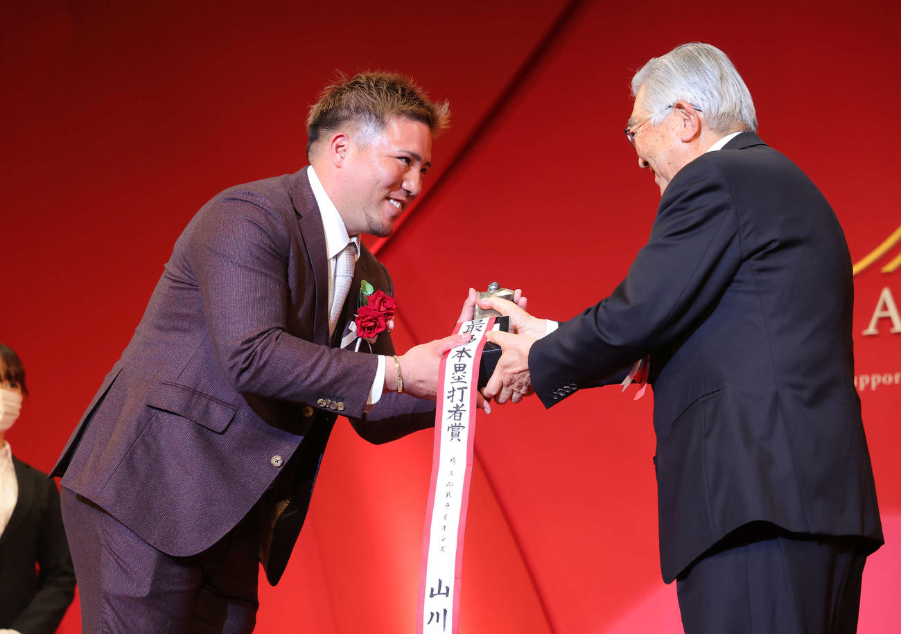 「NPB AWARDS 2022」でパ・リーグ最多本塁打者賞、最多打点者賞の2冠に輝いた西武山川（左）は斉藤コミッショナーから笑顔でトロフィーを受け取る（代表撮影）