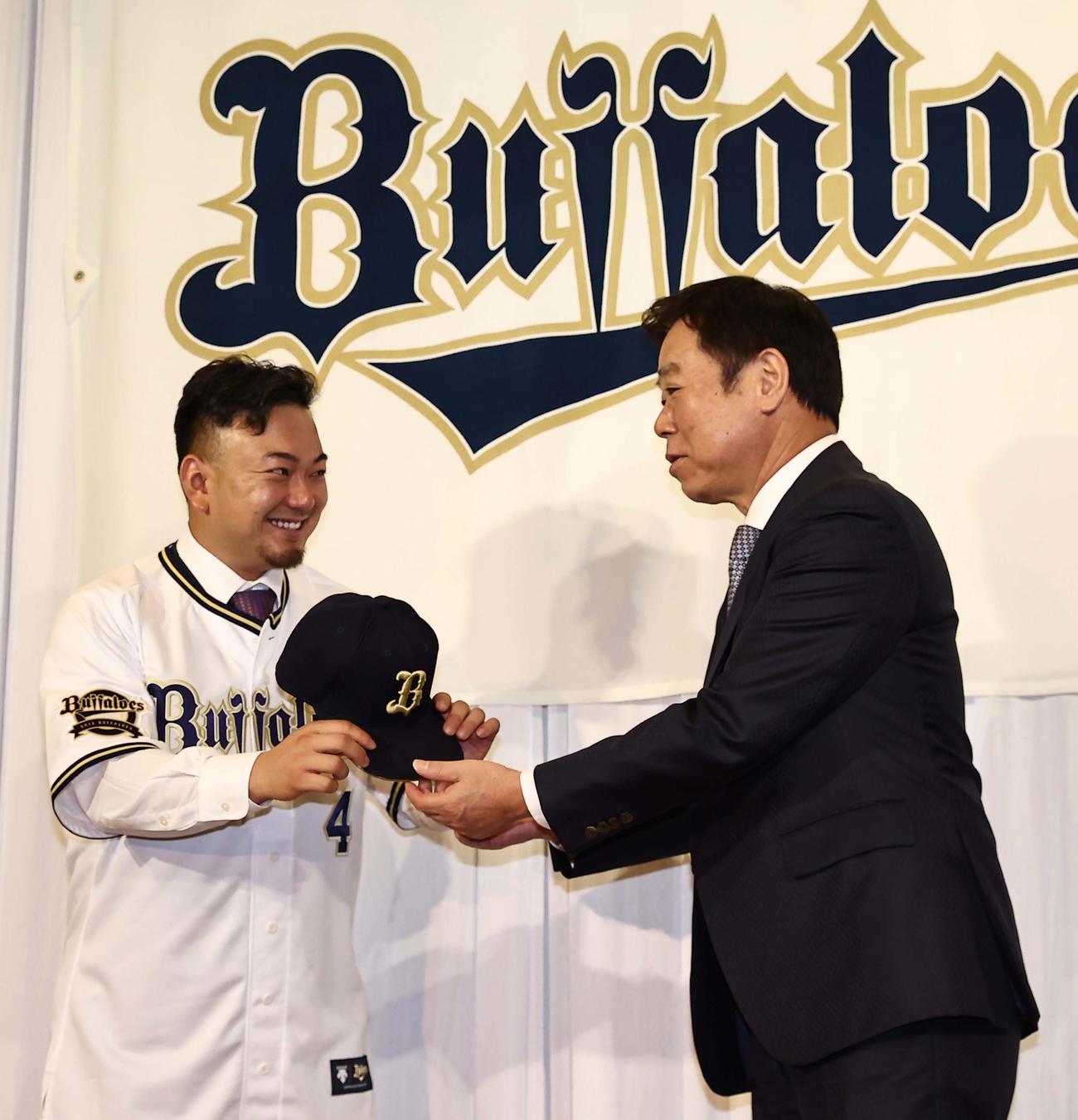 オリックスのユニホームを着た森友哉（左）は福良淳一GMから笑顔で帽子を受け取る（撮影・上田博志）
